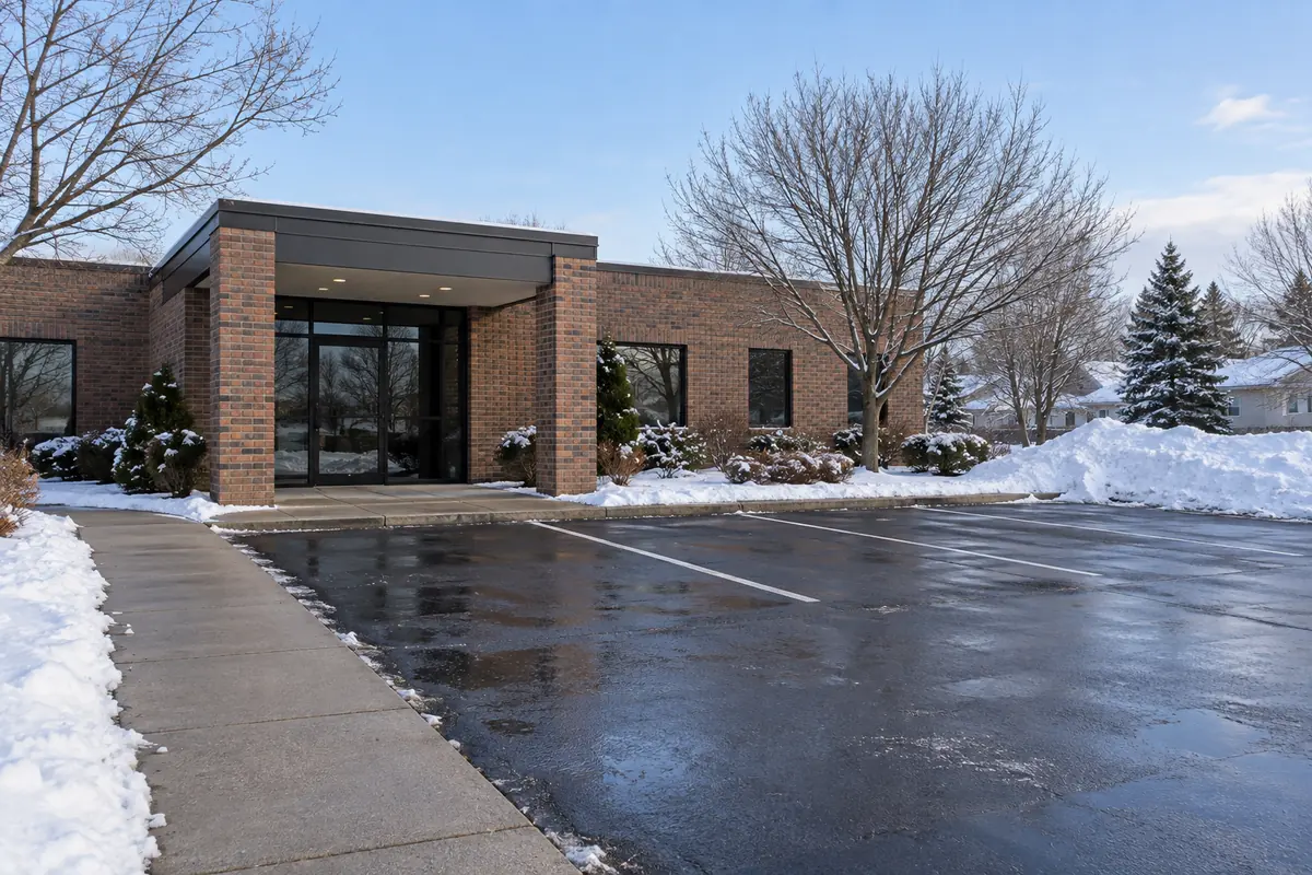 Cleared paved approach and parking spaces outside a small brick building